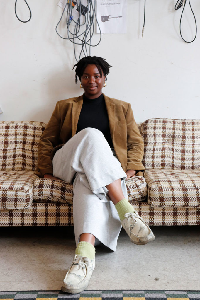 Vanessa sitter i en rutig soffa med benen i kors framför sig.